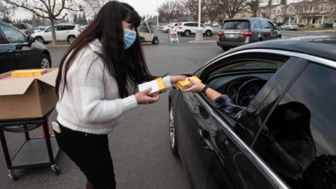 Pitman school employee Maria Johnson gives out COVID-19 rapid self test kits to students accompanied by a parent at Pitman High School in Turlock, Calif., on Thursday, Jan. 13, 2022. ANDY ALFARO AALFARO@MODBEE.COM