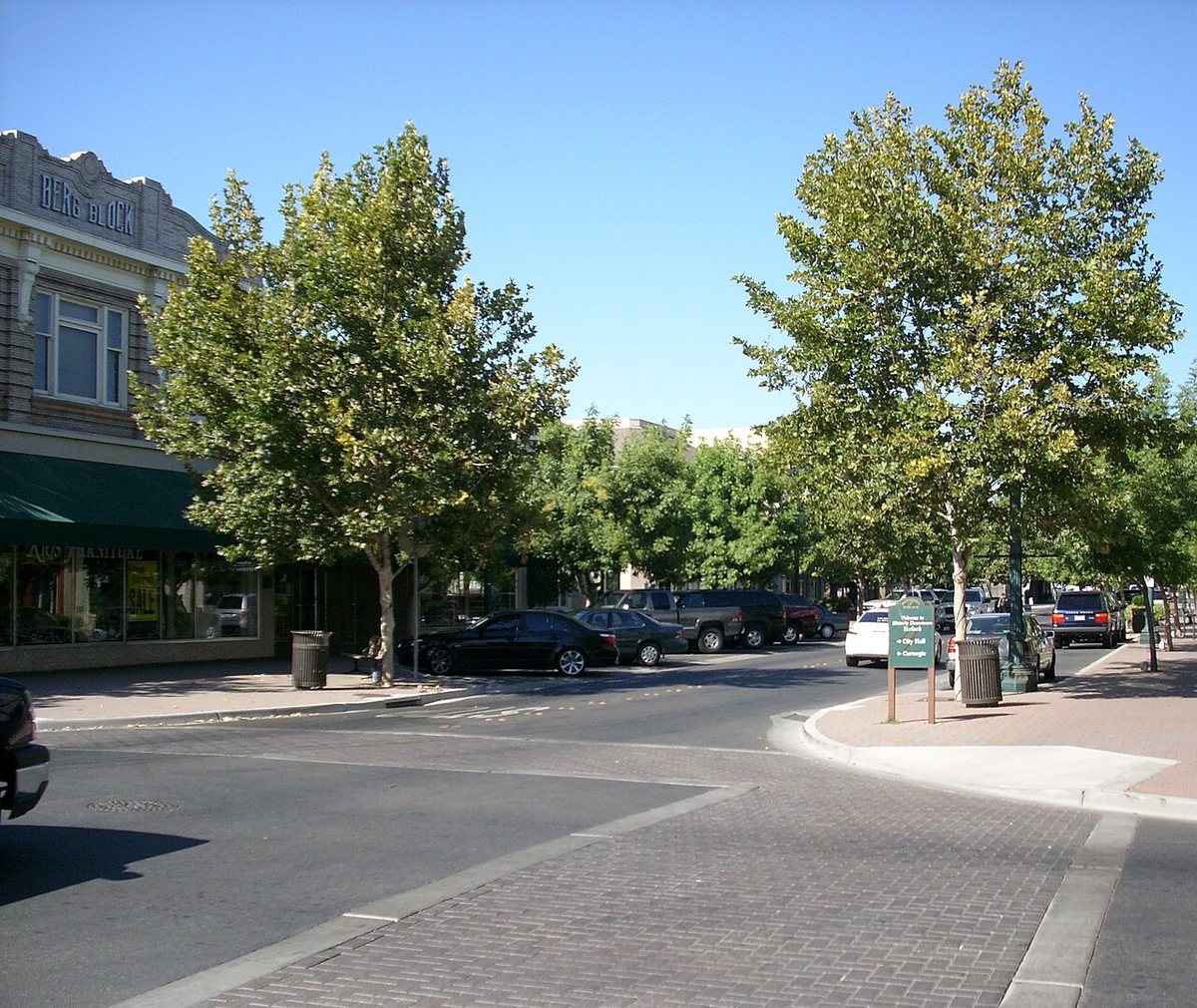 Main Street in downtown Turlock with storefronts, parked cars and street trees.