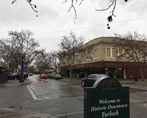 Downtown Turlock storefronts and street trees on a rainy day.