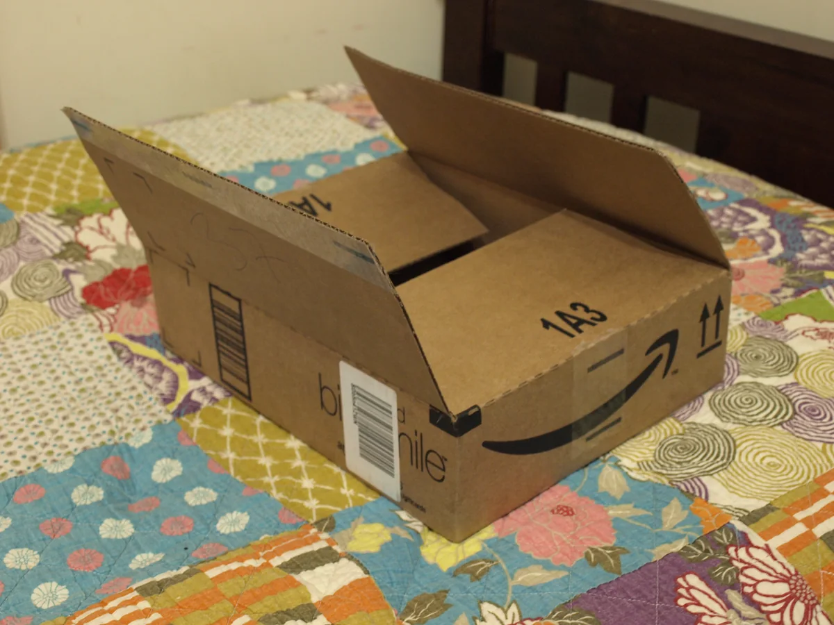 An open cardboard Amazon shipping box with the company smile logo.