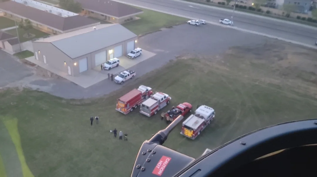 An aerial view of fire apparatus and personnel beside a large building.