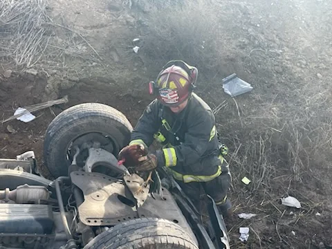 A firefighter works beside an overturned vehicle.