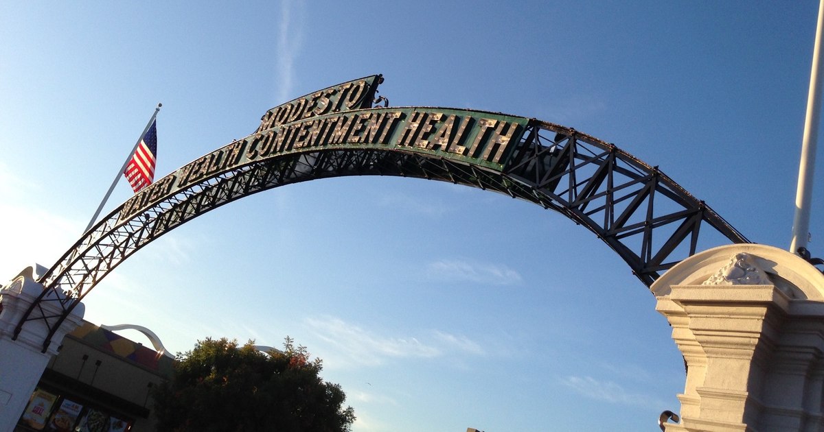 The Modesto Arch and its Water Wealth Contentment Health sign against a blue sky, photographed in January 2016.