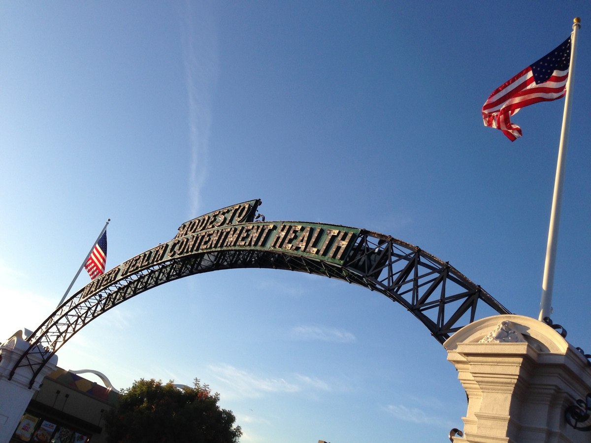 The Modesto Arch and its Water Wealth Contentment Health sign against a blue sky, photographed in January 2016.