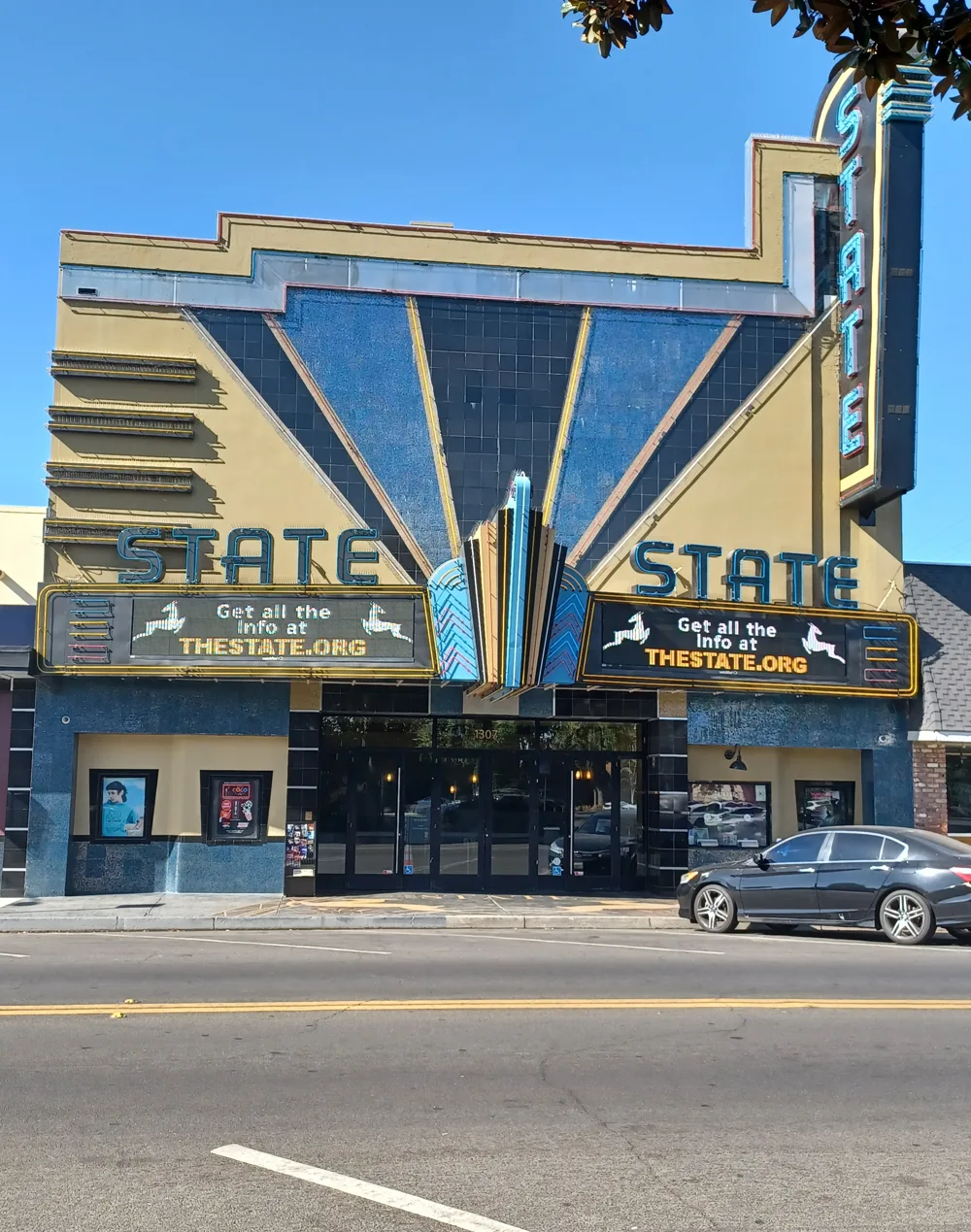 The blue and gold Art Deco facade and marquee of The State Theatre on J Street in Modesto, photographed in October 2023.